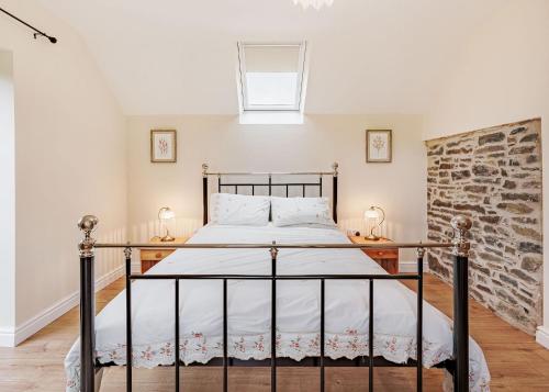 a bedroom with a bed and a brick wall at Sgubor Fach in Pen-y-bont-fawr