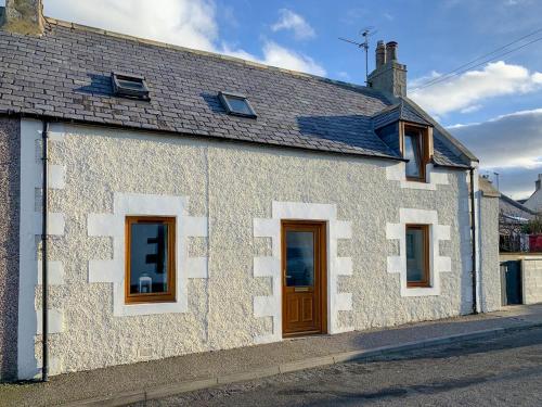 un edificio blanco con una puerta marrón en una calle en Seahaven Cottage, en Portknockie