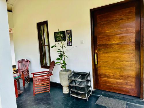 Zimmer mit Holztür und Topfpflanze in der Unterkunft Charitha Rest in Ampara