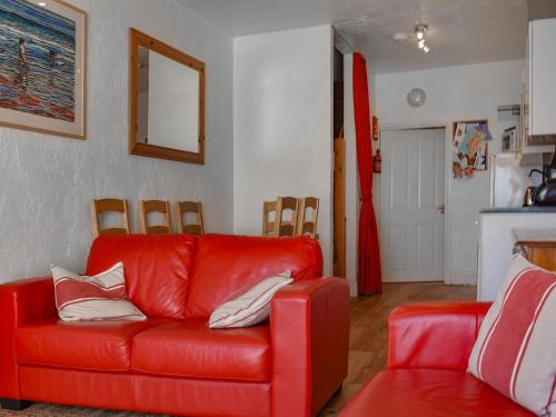 a living room with a red couch and a chair at Seaview Retreat in Appledore