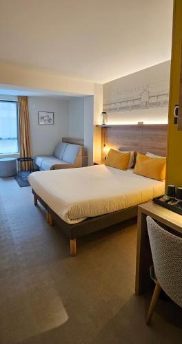 a hotel room with a large bed and a couch at Hôtel des Halles in Dijon