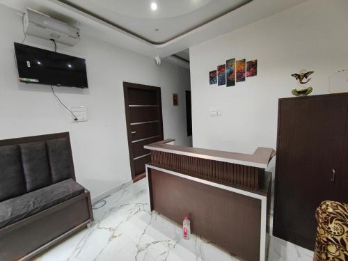 Una sala de estar con televisión y un sofá. en Shri Arpanam Home Stay, en Varanasi