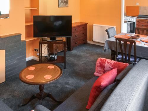 a living room with a couch and a tv and a table at 5 Rose Cottages in Sandhurst