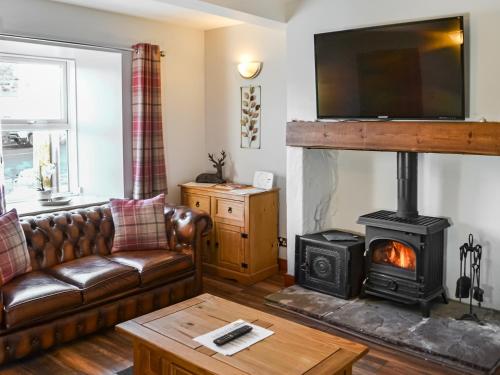 a living room with a couch and a wood stove at Mill Cottage in Belford