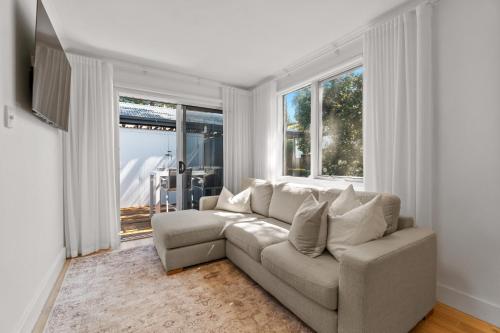 un salon avec un canapé et deux fenêtres dans l'établissement Stylish 2-Bed Townhouse in Leafy Hyde Park, à Unley