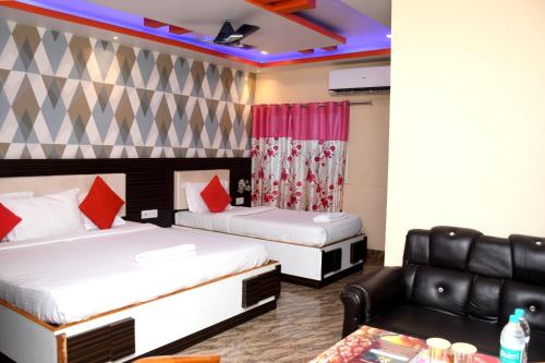 a hotel room with two beds and a couch at Hotel New Jasmine in Cuttack