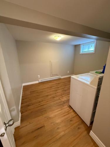 an empty room with a refrigerator and wooden floors at Vinnecomb Apartments - Lower Floor - 2 Bedroom in St. John's