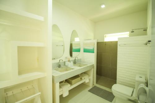 a white bathroom with a sink and a toilet at Pe na Areia Boutique Hotel in Japaratinga