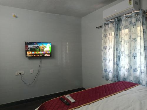 a bedroom with a tv hanging on the wall at LAkSHMI HOMESTAY in Tirupati