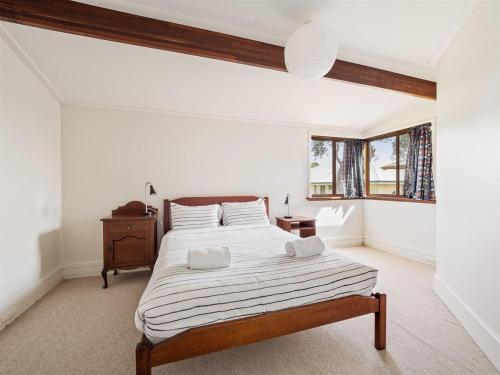 a white bedroom with a bed and a window at Mooring B on the shoreline in Augusta