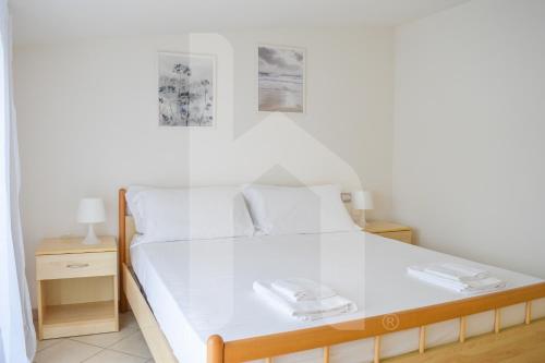 ein Schlafzimmer mit einem weißen Bett mit zwei Platten darauf in der Unterkunft Homiday - Green Bay Village in Pineto