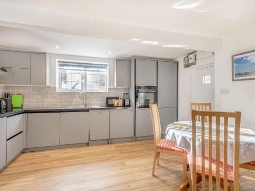 a kitchen with white cabinets and a table and chairs at Two Little Ducks in Wells next the Sea