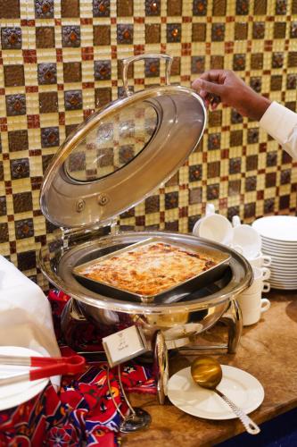 a person putting a pizza in a pan on a table at Verta Quraish Hotel in Jeddah