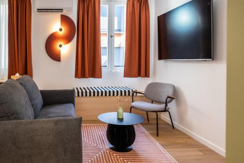 a living room with a couch and a table and a tv at Hôtel De L'Ill in Strasbourg