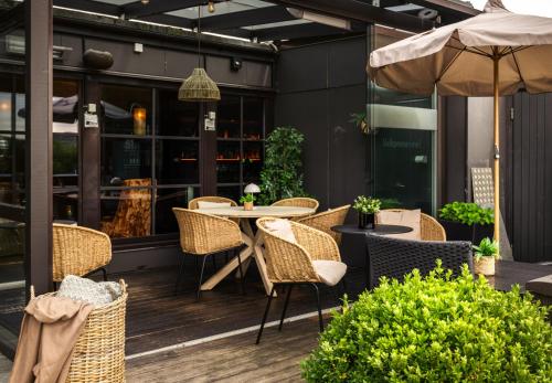 a patio with chairs and a table and an umbrella at Ågotnes Hotell in Ågotnes