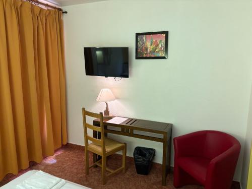 a room with a desk and a chair and a tv at Hotel Couleurs Sud Centre-ville Gare Charleville-Mézières in Charleville-Mézières