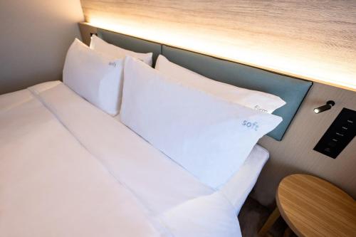 a room with a bed with pillows and a table at ANA Holiday Inn Iwate Kitakami by IHG in Kitakami