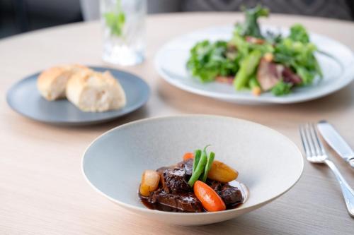 a table with plates of food and a plate of vegetables at ANA Holiday Inn Iwate Kitakami by IHG in Kitakami