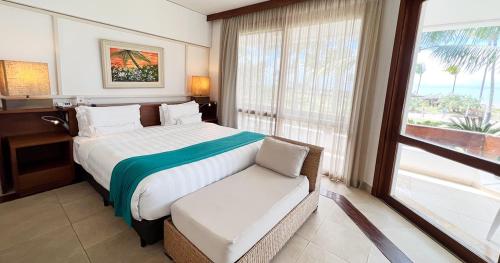 a hotel room with a large bed and a chair at Transamerica Comandatuba - All Inclusive Resort in Ilha de Comandatuba