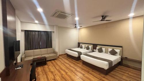 a hotel room with two beds and a tv at Hotel Kalyan Suites in Bengaluru