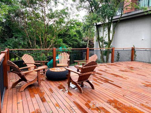 three chairs and a table on a wooden deck at Storia Gramado in Gramado