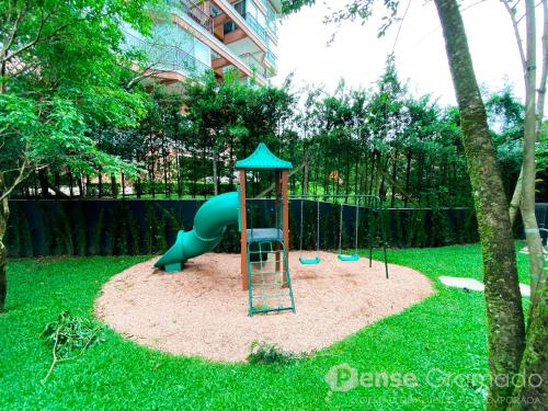 a playground with a blue slide in the grass at Storia Gramado in Gramado