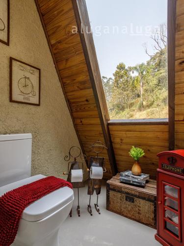 a bathroom with a toilet and a large window at Chalé Alcântara - Com banheira para casal in São Pedro de Alcântara