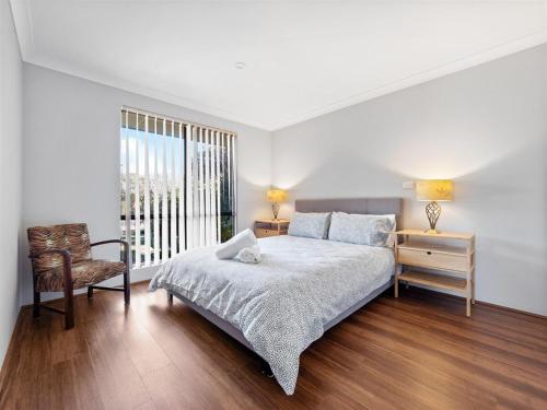 ein Schlafzimmer mit einem Bett und einem Stuhl und einem Fenster in der Unterkunft Leeuwin Cottage in Augusta