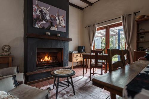 a living room with a fireplace and a table and chairs at Be My Guest Lodge in Bloubergstrand