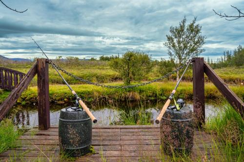 a wooden bridge with two trash cans on it at Riverside Cabin - Hot Tub, Fishing and Relaxing Escape in Laugarvatn