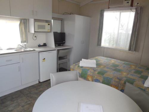 a white kitchen with a white table and a white refrigerator at Wodonga Caravan & Cabin Park in Wodonga