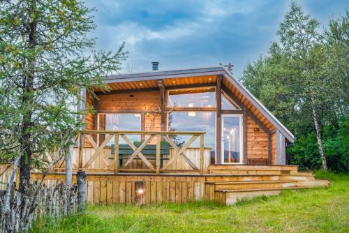 a log cabin with a large window and stairs at Riverside Cabin - Hot Tub, Fishing and Relaxing Escape in Laugarvatn