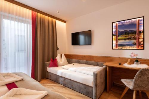 a hotel room with a bed and a desk at Hotel ALPINJUWEL 3-Sterne Superior in Gerlos