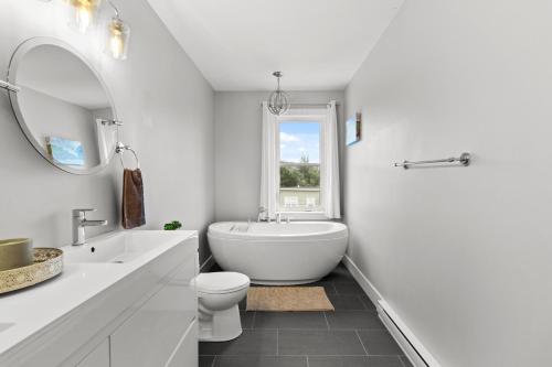 a bathroom with a tub and a toilet and a sink at Pennywell Prestige 3 Bed 15 Bath Garage in St. John's