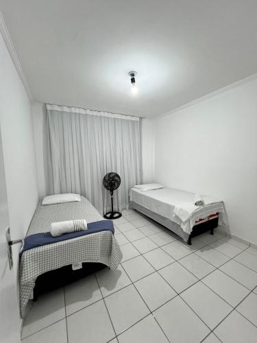 a white room with two beds and a fan at Apartamento Central 2 quartos e 2 banheiros, perto shopping in Juazeiro
