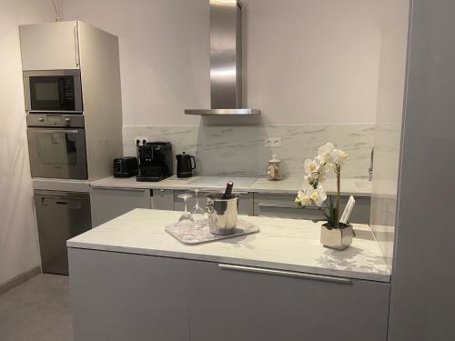 a white kitchen with a counter with flowers on it at AU COEUR DES LICES *** CENTRE HISTORIQUE AVIGNON in Avignon