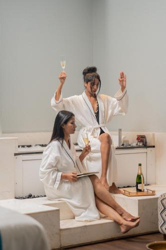 a man and woman sitting on a bed with champagne glasses at W Goa in Vagator