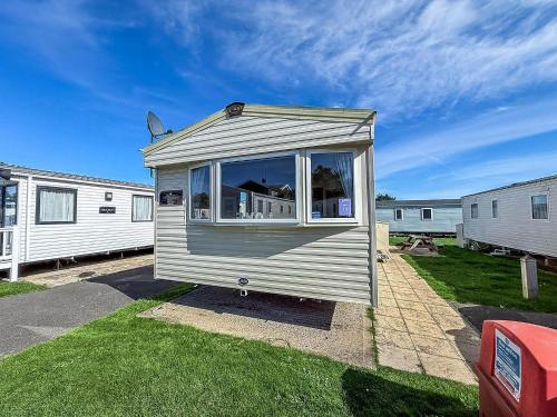 a tiny house is sitting in the grass at Superb 8 Berth Caravan, Close To Amenities At Caister Beach Ref 30073F in Great Yarmouth