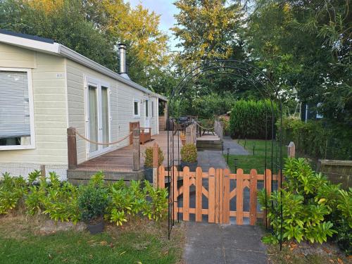 a wooden fence in front of a house with a yard at Chalet Ankerplatz in Lauwersoog in Lauwersoog