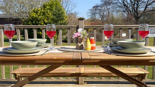 a wooden table with plates and glasses of red wine at The Tummel Lodge with Hot Tub in Crieff in Crieff