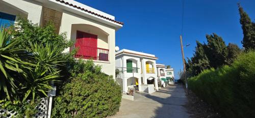 a white building with a red window on a street at Barefoot Beach House in Larnaca