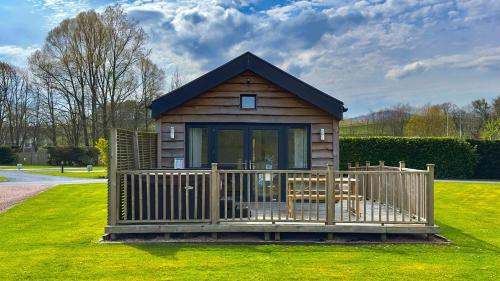 a small cabin with a porch and a fence at The Tummel Lodge with Hot Tub in Crieff in Crieff