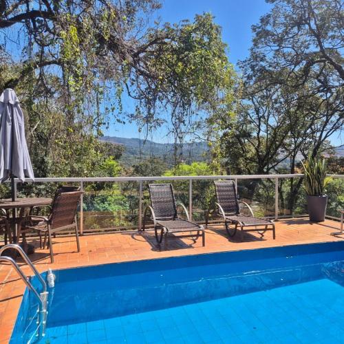 a patio with a table and chairs and a swimming pool at Casa Aquarela - Macacos, MG in Nova Lima