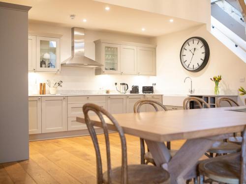 a kitchen with a table and a clock on the wall at Olivers Barn - Uk42081 in East Garston