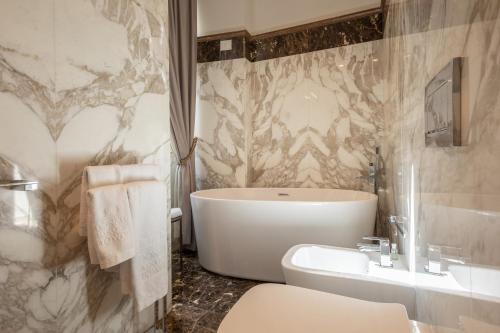 a bathroom with a tub and a toilet and a sink at Donati Luxury Tower Suites in Florence