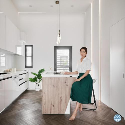 a woman standing at a kitchen island in a kitchen at 眺浪島民宿 in Fan-shu-liao