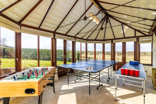 two ping pong tables in a room with windows at King Beds Hot Tub Games Room BBQ in Bunny