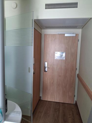 a bathroom with a wooden door and a toilet at Chambre privée avec lit double et sanitaires et TV mural in Bussigny