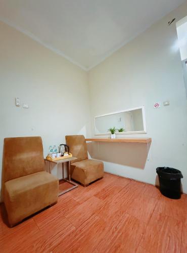 a room with two chairs and a table and a window at URVANA Hotel By Majestra Hospitality in Kamparganya