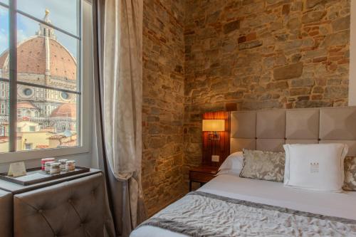 a bedroom with a bed and a brick wall at Donati Luxury Tower Suites in Florence
